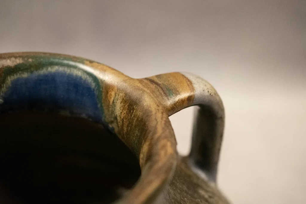 Vase japonisant en grès émaillé de Léon Pointu à trois anses chantournées et coulures blanc, bleu violacé et brun. Vue détail anse et col.