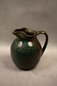 Pichet en grés émaillé, couverte brune avec coulures bleues Signé du cachet de Michel et Denise Pointu - vue de profil, anse à droite 2, portrait.