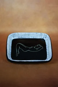 Plat rectangulaire en céramique à décor gravé d'une femme nue allongée sur email noir - Atelier Cerenne, Vallauris. De face, format portrait.