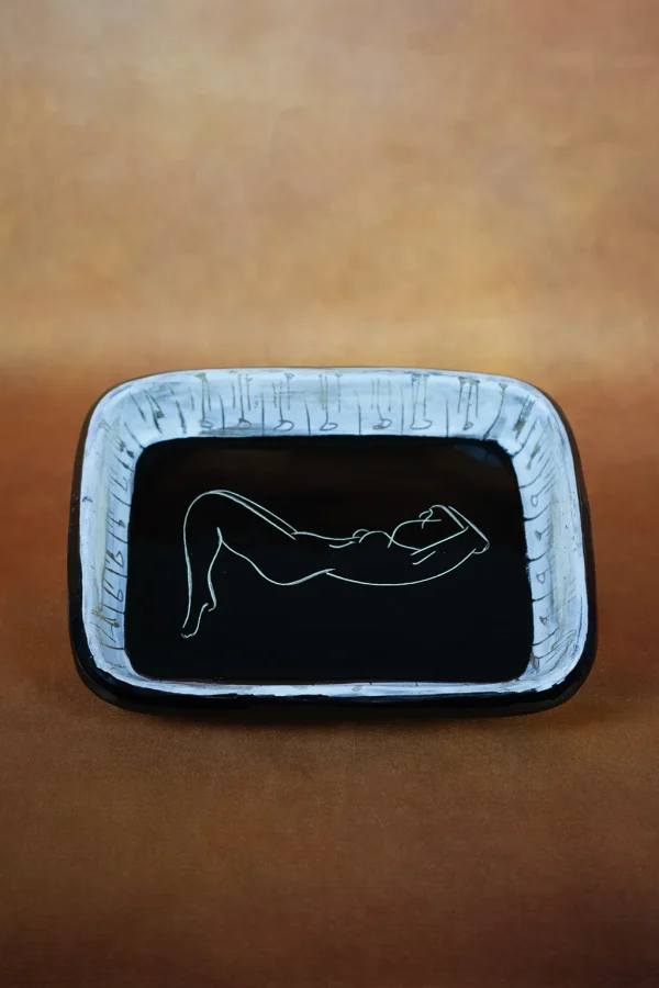 Plat rectangulaire en céramique à décor gravé d'une femme nue allongée sur email noir - Atelier Cerenne, Vallauris. De face, format portrait.