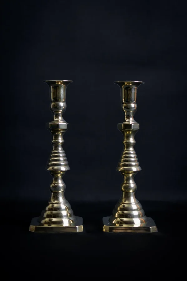 Paire de chandeliers victoriens en cuivre et laiton sur fond sombre.