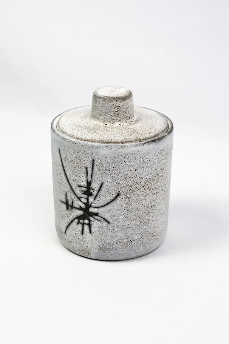 Vue trois-quarts du pot couvert Henri Cimal, texture bullée de l'émail blanc-gris, couvercle à bouton cylindrique