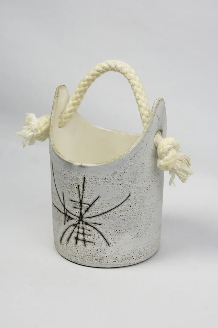 Vue trois-quarts du seau à glaçons en céramique émaillée d'Henri Cimal, anse tressée et nœuds frangés visibles