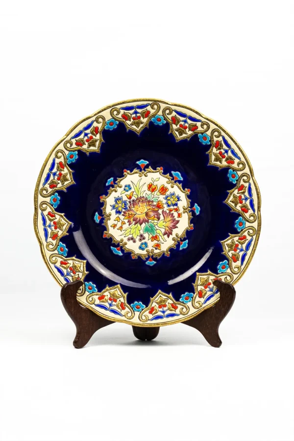 Assiette Émaux de Longwy modèle Renaissance, vue de face sur présentoir, fond bleu de sèvres, médaillon floral central polychrome rehaussé or