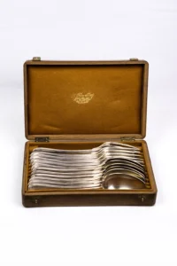 Coffret bois Christofle ouvert de face, fourchettes et cuillères argentées empilées en éventail sur feutrine