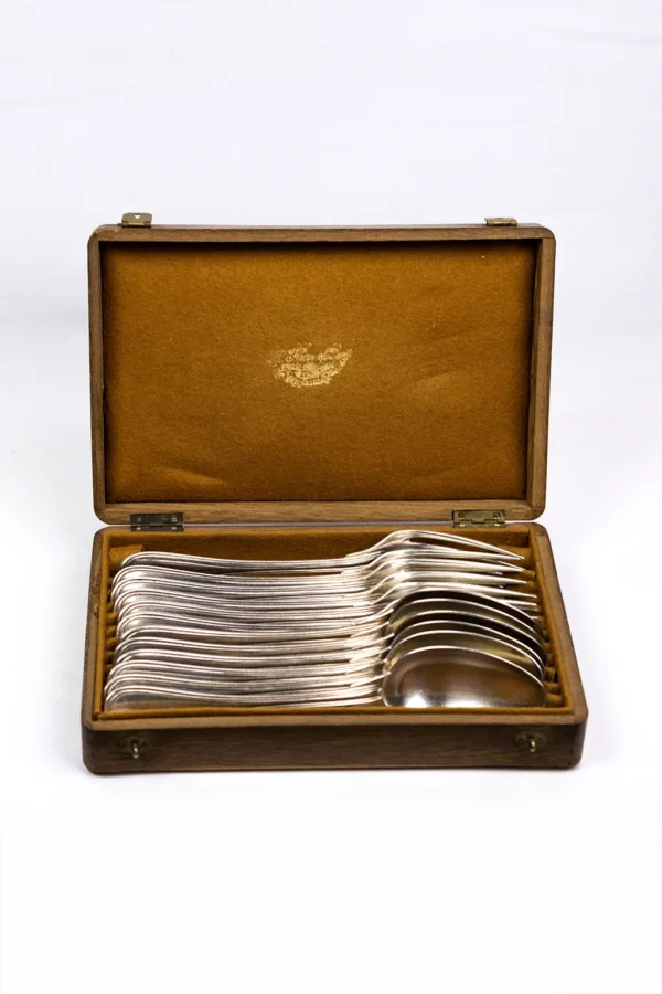 Coffret bois Christofle ouvert de face, fourchettes et cuillères argentées empilées en éventail sur feutrine