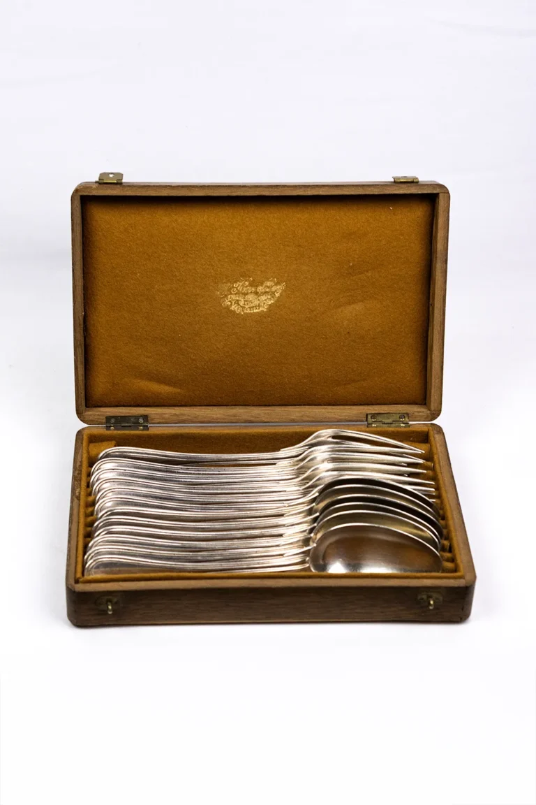 Coffret bois Christofle ouvert de face, fourchettes et cuillères argentées empilées en éventail sur feutrine